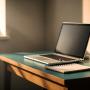 Image of a laptop sitting on a desk with a notebook and coffee cup beside it